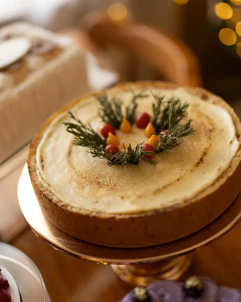 Torta inteira decorada com coroa de alecrim e tomatinhos, servida em suporte dourado